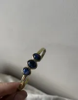 Pulsera rígida de bronce color dorado con tres piedras de ágata blancas de forma ovalada.