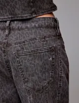 Pantalón de jean tiro alto con corte wide leg, confeccionado en denim gris oscuro con estampado de leopardo sutil. Presenta recortes verticales frontales y ruedo deshilachado.