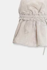 Top crop blanco con acabado foil brillante, cuello halter y escote pronunciado en pico. Presenta frunces en el bajo y un cordón ajustable en el centro inferior.