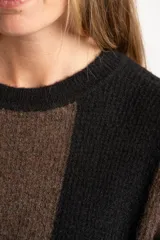 Sweater de tejido de punto grueso, con diseño de rayas verticales anchas en tonos marrón oscuro y negro. Presenta cuello redondo y mangas largas.