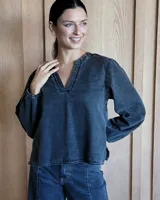 Blusa celeste de manga larga con escote en V y detalle bordado en el cuello.