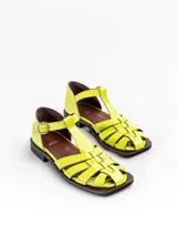 Sandalias tipo guillermina Bliss de cuero charol color amarillo, con capellada entretejida, tira en T y cierre de hebilla lateral. Posee suela plana y taco bajo.