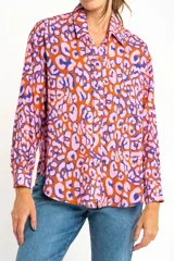 Camisa de viscosa color naranja con estampado animal print en tonos rosa y azul. Corte oversize, cuello clásico y cierre frontal con botones.