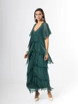 Vestido largo de seda italiana color verde oscuro, con capas escalonadas con flecos, escote en V con detalle de paillettes y mangas cortas fluidas.