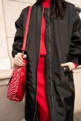 Campera bomber larga color negro, de nylon, con cierre frontal y bolsillos laterales.