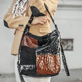 Cartera tipo morral confeccionada en cuero vacuno negro y marrón con diseño de bloques. Tiene una manija corta y una correa larga ajustable. En cada uno de sus dos lados tiene un amplio bolsillo vertical con cierre. En su tapa trasera tiene un bolsillo con cierre. Su interior está forrado en tela de excelente calidad, y contiene un bolsillo con cierre y otro pequeño para el guardado del móvil.