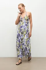 Maxi vestido largo de tirantes con cuello en V, corte fluido y estampado floral en tonos azules y verdes sobre base blanca.