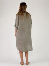 Camisola midi confeccionada en lino color gris, con diseño amplio y fluido, cuello camisero, cierre frontal con botones y mangas largas con presilla para arremangar.