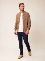 Cardigan de punto gris con cierre frontal completo, cuello tipo mao y puños acanalados. Presenta un pequeño logo bordado en el pecho y detalles en contraste en el interior del cuello y puños.