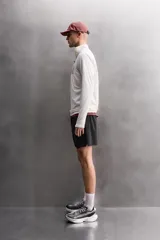 Pantalones cortos deportivos color marrón rojizo, confeccionados en tejido técnico ligero y elástico. Presentan cintura elástica ajustable con cordón interior, bolsillos frontales y un bolsillo trasero con cierre de cremallera. Los laterales tienen perforaciones para transpirabilidad y aberturas laterales en el bajo.