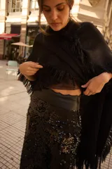 Pollera larga de lentejuelas negras con diseño de tajo lateral profundo. Presenta una cintura alta con banda lisa y corte recto que se ajusta a la silueta.