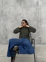 Polera de punto acanalado en color verde oliva, con cuello alto abierto lateralmente y mangas largas amplias. Presenta un diseño de corte recto y holgado.