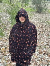 Buzo color beige de poliéster con textura de piel de oso, capucha con cuello alto, mangas largas y bolsillo tipo canguro.