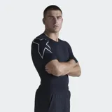 Remera deportiva de compresión color negro, de manga corta, con costuras planas y detalle gráfico reflectante en la manga derecha.