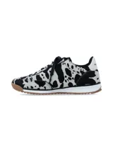 Championes urbanos con diseño de estampado animal print tipo vaca en blanco y negro, con detalles en blanco en los laterales, cordones negros y suela de goma dentada en color marrón.