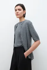 Cardigan gris melange de tejido de punto con diseño texturizado, manga corta y cierre frontal con botones.