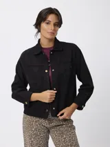 Campera de estilo camisero con efecto gamuzado, color beige, de corte recto y holgado. Presenta cuello clásico, cierre frontal con botones, mangas largas con puños abotonados y bolsillos frontales aplicados.