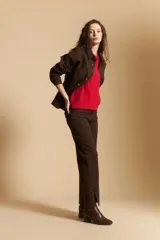 Pantalón de corte recto y tiro medio, color marrón, con detalle de tachas metálicas a lo largo de las costuras laterales y tajos en el ruedo.