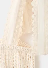 Top de punto calado color beige, con cuello recto, tirantes con cierre de lazo y detalles bordados.