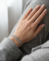 Pulsera esclava de acero con diseño de doble cadena de eslabones entrelazados.