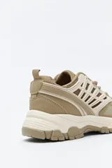 Zapatilla deportiva de estilo trekking con diseño técnico y urbano. Presenta una estructura combinada de paneles de malla y piezas de poliuretano, con sistema de cordones integrado y suela robusta con relieve para mayor estabilidad.