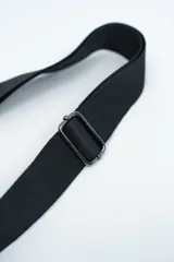 Bandolera de diseño rectangular en color negro, confeccionada en material texturizado. Cuenta con una correa de hombro ajustable y extraíble, cierre superior y tiradores laterales decorativos.