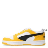 Championes Puma Rebound V6 Low de estilo urbano, con diseño de bloques de color en amarillo, blanco y negro. Presentan una parte superior de cuero sintético con perforaciones en la puntera, cierre de cordones y suela de goma con amortiguación en el talón.