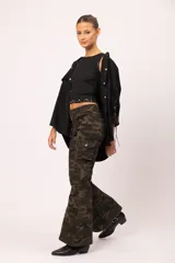 Musculosa negra de calce entallado, con cuello redondo y detalle de tachas piramidales, estrellas y ojalillos metálicos en el borde inferior.