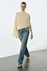 Jeans de tiro medio con corte slim y largo completo. Presentan diseño de cinco bolsillos, cierre frontal con cremallera y botón, efecto lavado y detalle de rotura en la parte delantera con bajo sin costura.