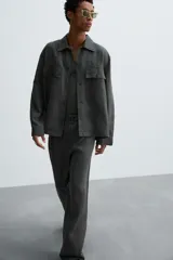 Pantalón de corte relajado confeccionado en tejido de cáñamo color blanco roto. Presenta cintura elástica con cordón interior ajustable, cierre frontal con botones, bolsillos laterales y un bolsillo trasero de plastrón.
