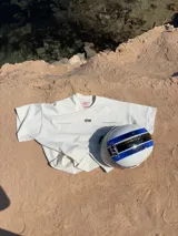 Remera marrón de corte holgado con estampado en la espalda que incluye la palabra "ITTAI" en blanco con líneas rojas y azules, la frase "AN IBIZA PRODUCE" y un texto más pequeño que dice "Ittai Stars Department Gallery - Ibiza Edition. If you're in Ibiza, 112 is not an option.".