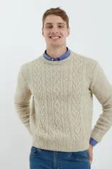 Sweater de tejido de punto color beige claro, con diseño de trenzas (aranes) en el frente y mangas de punto liso. Tiene cuello redondo.