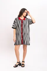 Vestido camisola corto de tejido fresco de algodón, con diseño de rayas verticales en blanco y negro. Presenta cuello polo, solapa y ribete central con botones en color rojo.