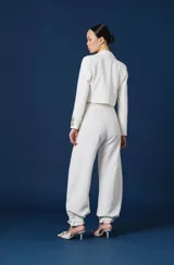 Saco corto tipo blazer color negro, de corte entallado y manga larga. Presenta un detalle distintivo en el puño izquierdo con una banda en tono dorado que incluye la inscripción 'ANTOLIN'.