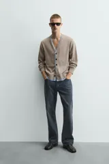 Cárdigan de punto con cuello en pico y manga larga. Presenta un diseño de ajuste relajado con cierre frontal de botones y acabados en rib con efecto doble en color azul a contraste sobre la base color topo.