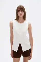 Chaleco de lino blanco, sin mangas, con cuello redondo y cierre frontal con botones.