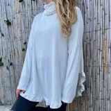 Polerón blanco de morley con cuello alto y volados en ruedo y puños.