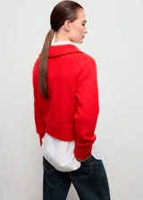 Cardigan de punto grueso color rojo, con diseño recto, cuello camisero, cierre frontal de cremallera doble y mangas largas con puños acanalados.