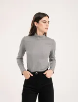 Polera gris de rib elastizado con brillos, cuello alto y mangas largas.