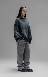 Hoodie oversize de corte crop en color gris oscuro con efecto desgastado. Presenta costuras expuestas, detalles de roturas en el ruedo y en la capucha, y bolsillos frontales con bordes reforzados.
