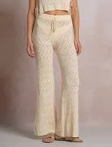 Pantalón de tiro alto con tejido calado y textura labrada, de corte recto con apertura acampanada hacia el ruedo. Cuenta con cintura elastizada y cordón de ajuste con terminaciones de caracoles decorativos.