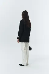 Blazer negro de lana con calce overfit y estética vintage. Presenta cierre frontal de dos botones, bolsillos exteriores y botones de cuerno natural grabados con logo.