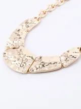 Collar de eslabones con piezas frontales de diseño curvo y acabado martillado en tono dorado.