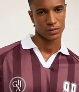 Remera deportiva de fútbol para hombre con cuello polo acanalado, mangas cortas, letras y rayas. Confeccionada con tecnología dry que absorbe el sudor.