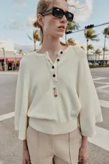 Jersey de punto liso color azul, con cuello redondo, botones delanteros y manga ancha por debajo del codo.