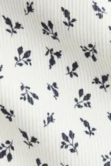 Remera ajustada de manga larga en punto acanalado blanco, con escote cuadrado ribeteado en encaje y un pequeño moño de satén en el centro del escote.