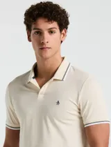 Chomba color crema de manga corta con cuello clásico y logo bordado en el pecho. Detalles de rayas en cuello y mangas.