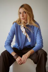 Cardigan azul de punto fino, con cuello redondo y cierre frontal de botones negros.