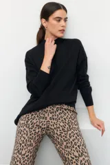 Polera de cuello alto y manga larga, con puños elásticos y aberturas laterales en el ruedo. Diseño holgado y minimalista.