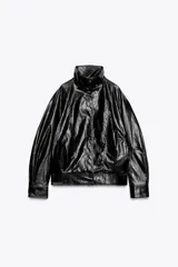 Chaqueta tipo bomber de efecto cuero en color negro, con cuello alto, cierre frontal con cremallera y botones a presión ocultos por solapa. Presenta mangas largas, bolsillos delanteros y bajo abullonado.